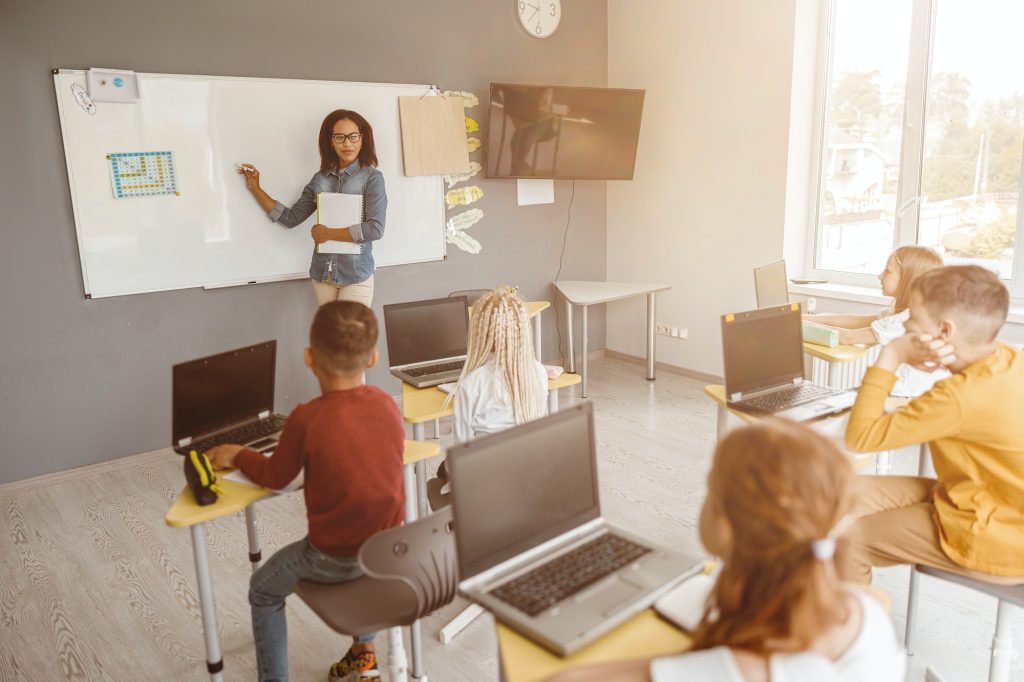 Afro American teacher writing on chalkboard in class